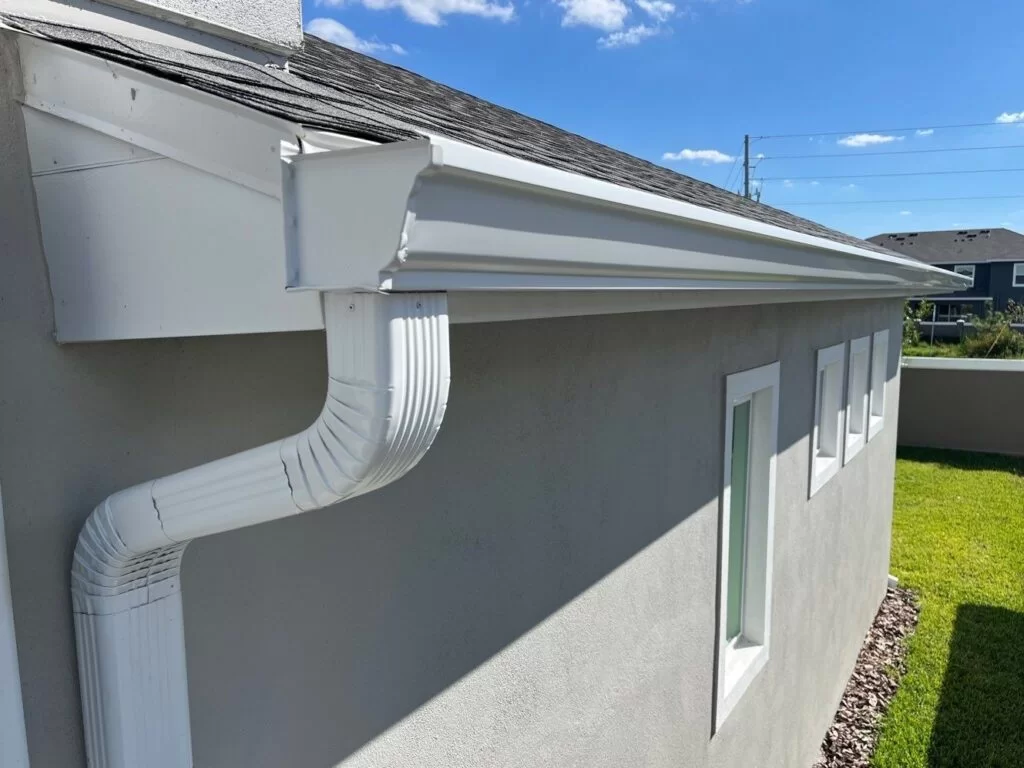 Close-up of a modern white rain gutter and downspout on a residential home